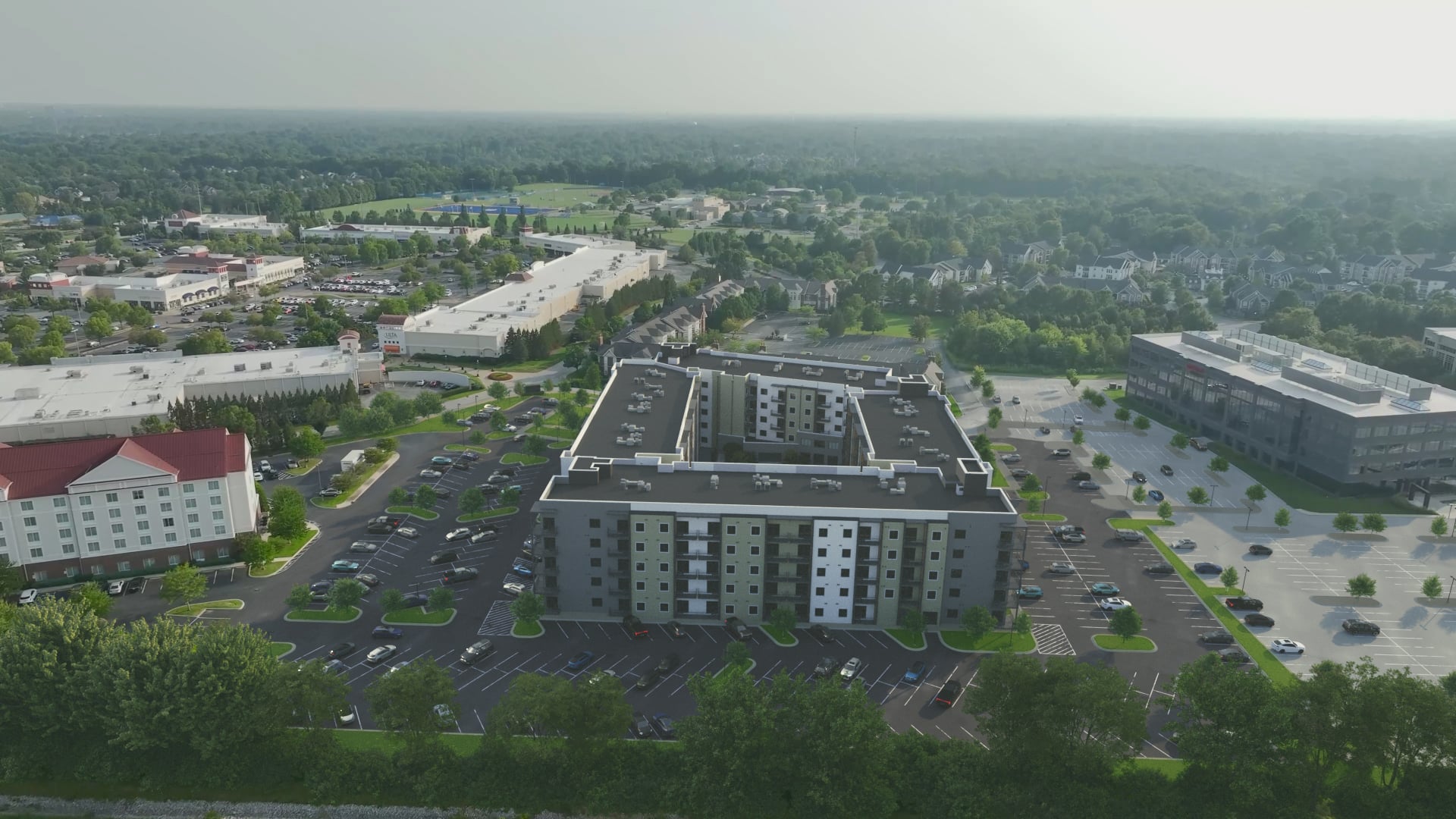 A large grey building with a parking lot in front of it.